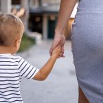 Una donna sta camminando tenendo per mano un bambino