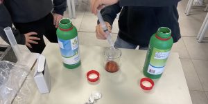 Una studentessa o uno studente versa del liquido con una siringa in un contenitore di vetro.