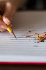 Persona che sta per scrivere sul quaderno a righe bianco