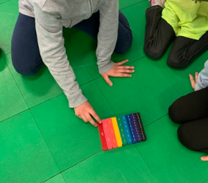 Bambine e bambini studiano un oggetto di vari colori diviso in parti che rappresentano frazioni