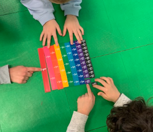 Bambine e bambini studiano un oggetto di vari colori diviso in parti che rappresentano frazioni
