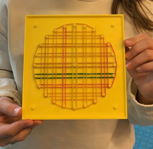 Una studentessa mostra la sua opera: linee parallele orizzontali e verticali il cui limite forma un cerchio