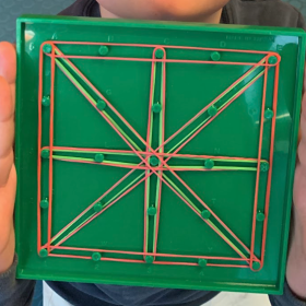 Uno studente mostra la sua opera: un quadrato con linee diagonali e che lo dividono a metà.