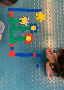 Due bambine costruiscono un mosaico che rappresenta alcuni fiori e un sole