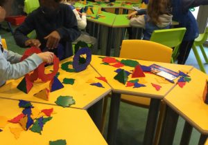 Bambine e bambini studiano figure geometriche tridimensionali incastrando assieme pezzi di plastica di forme diverse