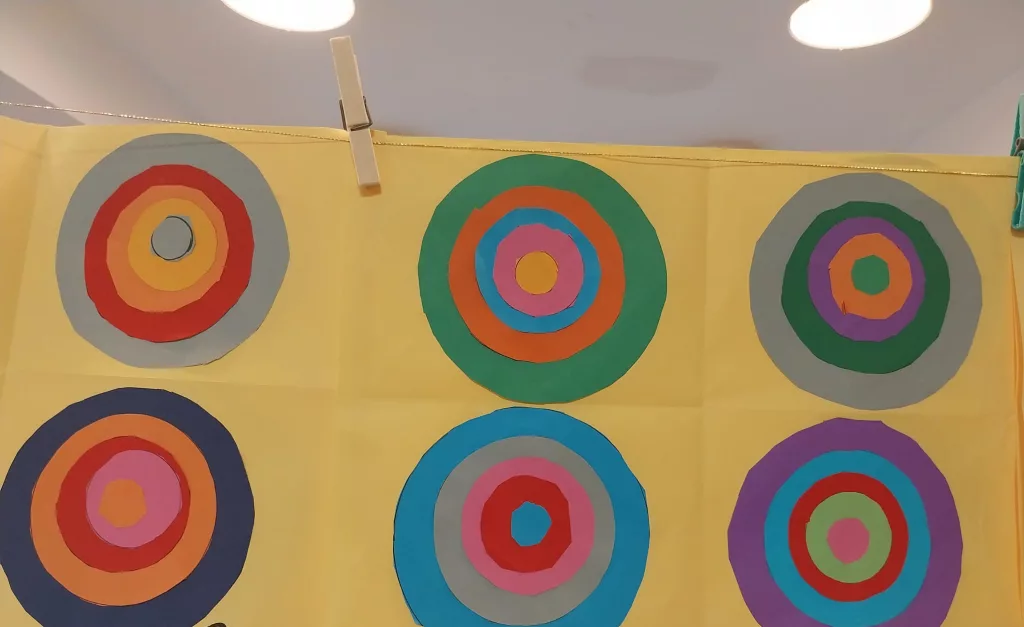 Sono presenti diversi fogli gialli, su ognuno dei quali sono presenti cinque cerchi concentrici impilati di colori diversi.